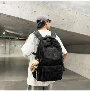 Urban lifestyle shot of a black camouflage backpack with a cute bear charm accessory.