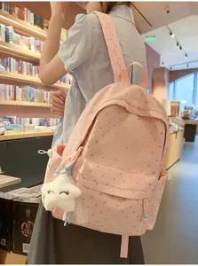 Detalle de mochila escolar rosa con patrón de corazones y colgante de estrella