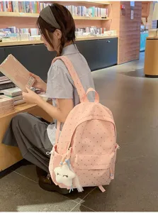 Detalle de una mochila escolar rosa con estampado de corazones en una biblioteca