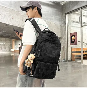 Detailed view of a black camouflage backpack with MGICH logo worn by an Asian model