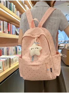 Mochila rosa con estampado de corazones y llavero de estrella en una biblioteca