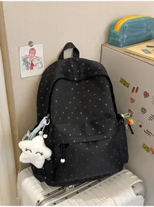 Mochila escolar negra con corazones y colgante de estrella de peluche en habitación