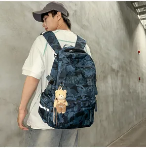 Close-up detail of blue camouflage student backpack with a cute bear plush keychain