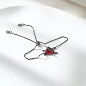 Detailed close-up of adjustable gothic red crystal heart dagger charm bracelet in black metal.