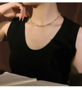 Close-up detail of an elegant natural pearl and green crystal necklace on a female model