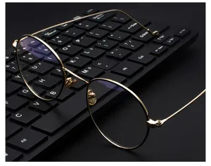 Vista detallada de elegantes monturas redondas doradas con lentes anti-luz azul en teclado