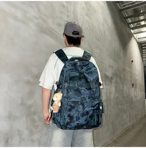 Large blue camouflage student backpack shown from the back with a cute bear keychain