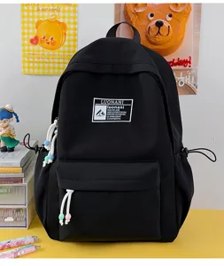 Vista ravvicinata di uno zaino scolastico nero minimalista con toppa del logo Luonani