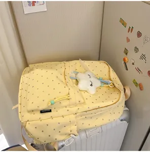 Mochila amarilla con corazones sobre maleta blanca con un lindo colgante de estrella