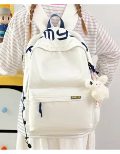 Back view of a white student backpack with blue embroidery and a cute plush bunny charm.
