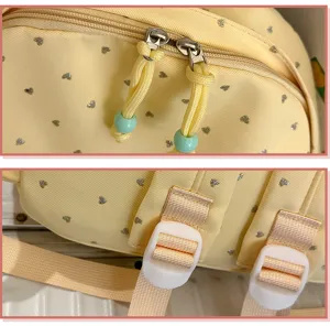 Primer plano de la cremallera y hebillas de una mochila amarilla con patrón de corazones.