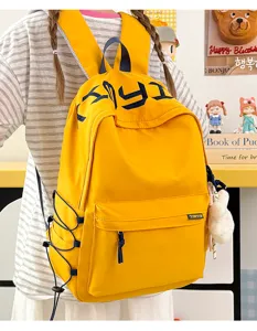 Close-up back view of a yellow student backpack with navy embroidery and bunny charm