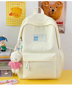 Zaino scolastico color crema stile coreano con ciondoli a forma di orsetto su una scrivania