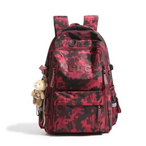 Front pocket detail of camo school backpack showing MGDCH lettering and plush bear charm