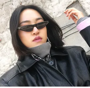 Asiatisches Model trägt eine schwarze Retro-Cat-Eye-Sonnenbrille zur Lederjacke.