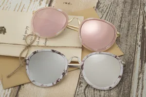Close-up of stylish round frame sunglasses in pink marble and silver mirrored finishes