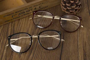 Primer plano de gafas con montura metálica en negro y granate sobre fondo madera