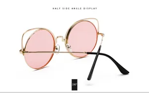 Detailed side view of vintage round sunglasses with pink lenses and gold cat-ear frames.