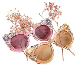 Fashionable women's floral rhinestone sunglasses with oversized frames in pink and orange.