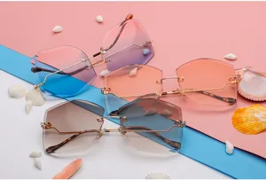 Primer plano de gafas de sol geométricas sin montura con cristales degradados y fondo de conchas