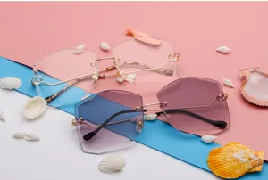 Detalle de gafas de sol geométricas sin montura con lentes degradadas moradas y patillas doradas.