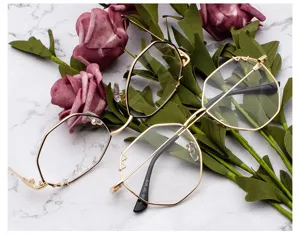 Détail de lunettes à monture métallique polygonale dorée sur marbre blanc