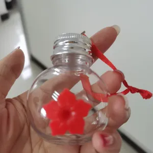 Handheld clear hummingbird feeder with red flower port and hanging ribbon detail view.