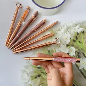 Detailed view of rose gold ballpoint pens set featuring diamond top and glitter barrel.