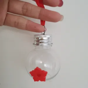 Handheld hummingbird feeder with bulb shape clear design and red flower feeding port.