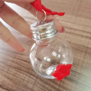 Handheld clear glass hummingbird feeder with red flower port and silver cap for outdoor garden.