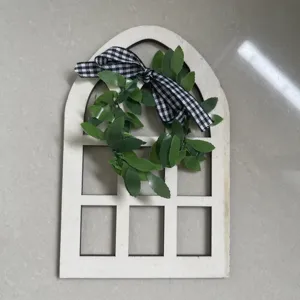 Close-up of wooden arched window frame detail featuring green leaf wreath and plaid bow.