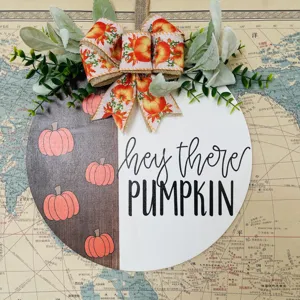 Autumn pumpkin wooden door sign detail view, rustic fall hanging decor with bow and leaves.