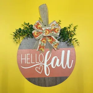 Detailed close-up of autumn pumpkin wooden hanging sign with burlap bow and green leaf decor.