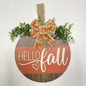 Wooden fall door sign detail featuring pumpkin bow and eucalyptus leaves for autumn decor.