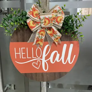 Close-up autumn pumpkin wooden door sign detail, rustic burlap bow and green foliage decor.