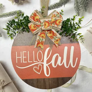 Close up detail view of the autumn wooden hanging sign with fall pumpkin bow and green foliage.