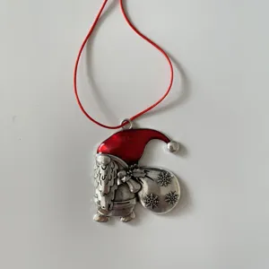 Detailed view of metal Christmas tree ornament with Santa gnome design and red hanging cord.