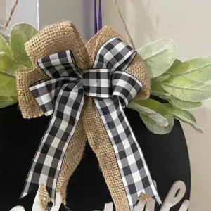 Detailed close-up of the rustic burlap and buffalo plaid bow with green leaves on the sign.