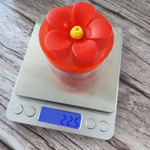 Handheld plastic hummingbird feeder with red flower cap, lightweight garden supply.