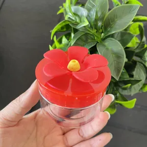 Close-up shot of a hand holding a mini hummingbird feeder featuring a cute red flower top.