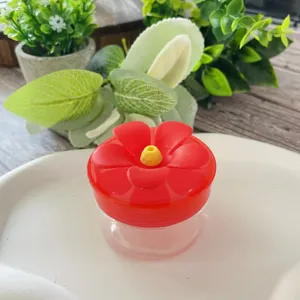 Detailed view of hand hummingbird feeder with red flower lid and clear jar container.