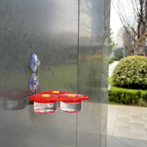 Hanging hummingbird feeder with suction cups and red flower feeding ports for outdoor use.