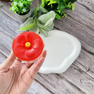 Detailed view of hand hummingbird feeder red flower top and clear base in lifestyle setting.