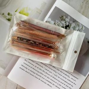 Detail view of a 6-piece rose gold and pink ballpoint pen set in clear packaging.