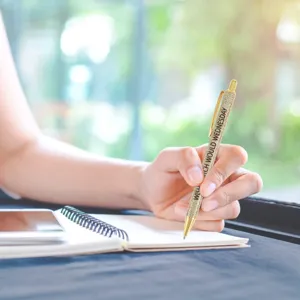 Close-up detail shot of a glitter ballpoint pen writing smoothly on a clean notebook in bright room.