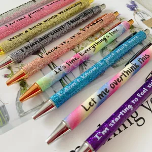 Detail view of colorful glitter ballpoint pens set with funny daily quotes for office.