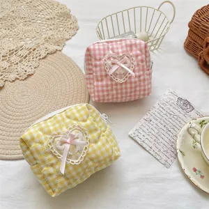 Quilted cosmetic bag detail featuring cute gingham pattern, lace heart and pink bow accents.