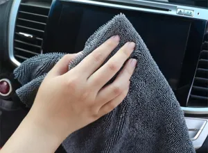 Dettaglio del panno in microfibra per auto che pulisce lo schermo del cruscotto.