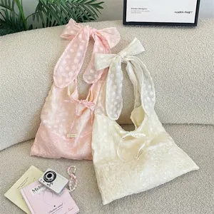 Detalle de bolsos tote de organza rosa y crema con lunares, lazos grandes y lentejuelas bordadas