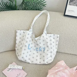 Detailed view of white canvas tote bag with star print and 'Lucky' embroidery.